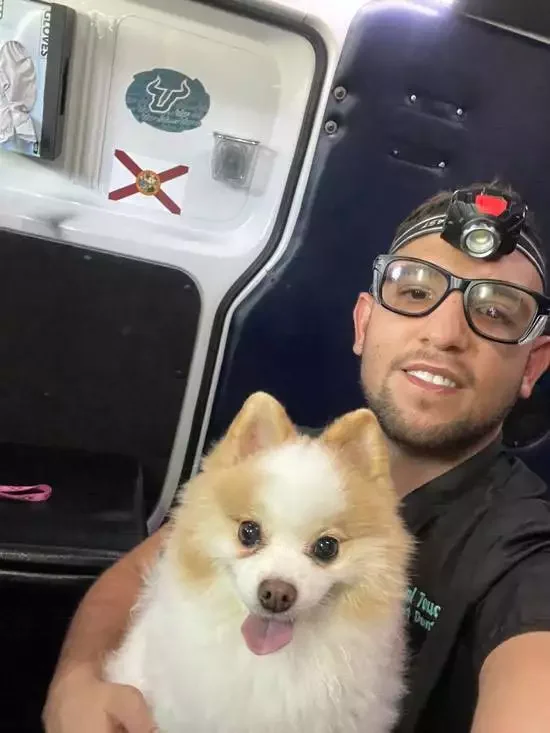 Pet dental technician holding a smiling Pomeranian in the mobile unit