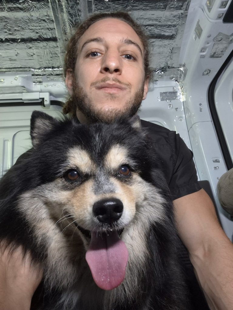 Royal Touch team member with a fluffy black and white dog in the dental van